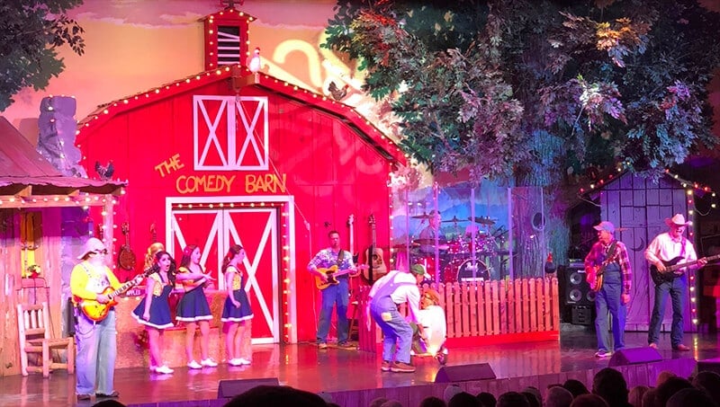 Performers in front of the red barn on the stage at the Comedy Barn in Pigeon Forge.