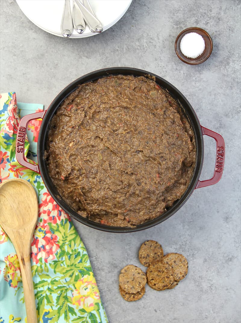 Overhead photo of black bean soup in a Dutch oven with a wooden spoon resting on a napkin.