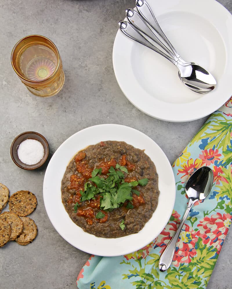 Overhead view of a bowl of easy black bean soup with a spoon resting on a napkin.