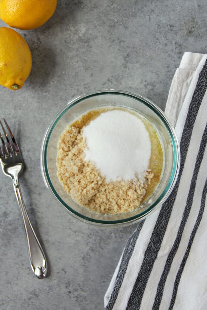A bowl of shortbread cookie crumbs, sugar, and butter for easy cheesecake bars.