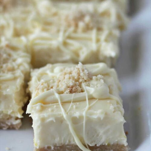 Side view of white chocolate cheesecake bars on a serving platter.