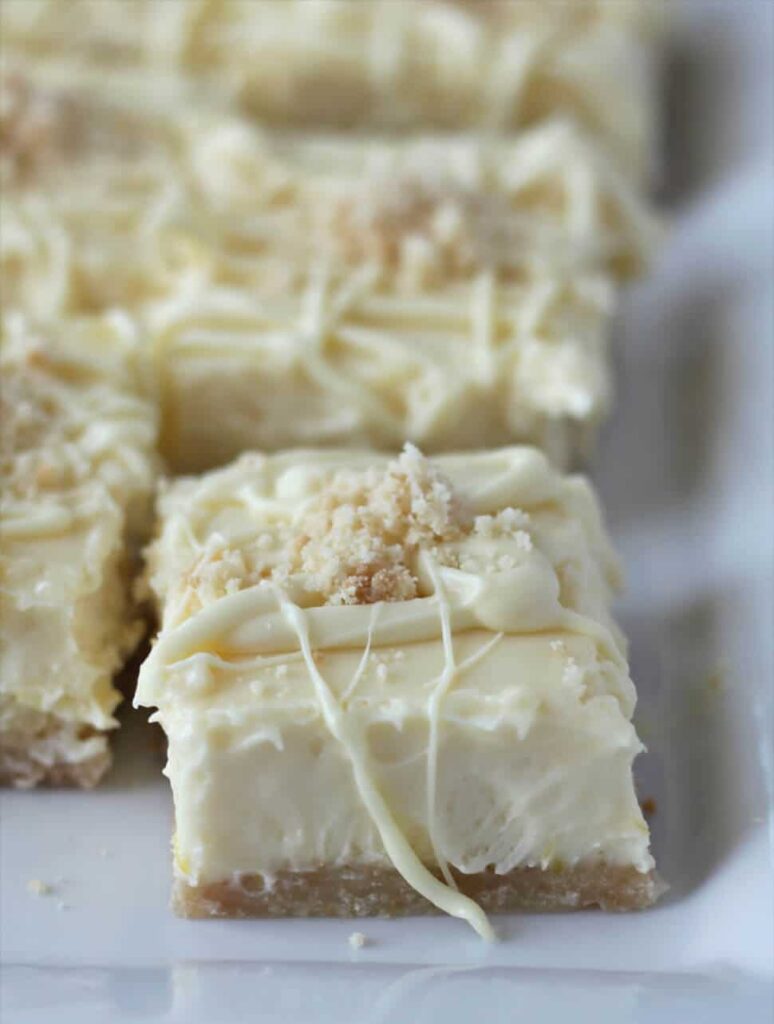 Side view of white chocolate cheesecake bars on a serving platter.
