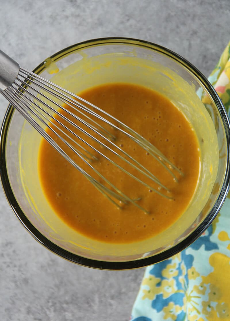 Whisk inside a bowl that contains homemade honey mustard. 
