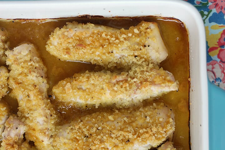 Closeup view of baked honey mustard chicken tenders in a white dish. 
