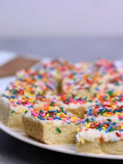 Sugar Cookie Bars with sprinkles and frosting on a plate.