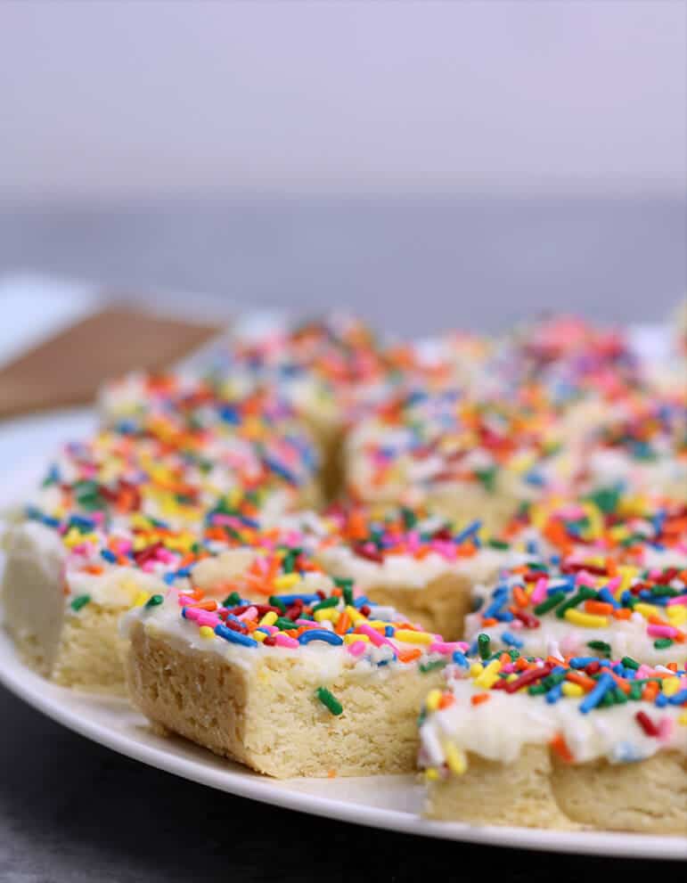 Sugar Cookie Bars with sprinkles and frosting on a plate. 