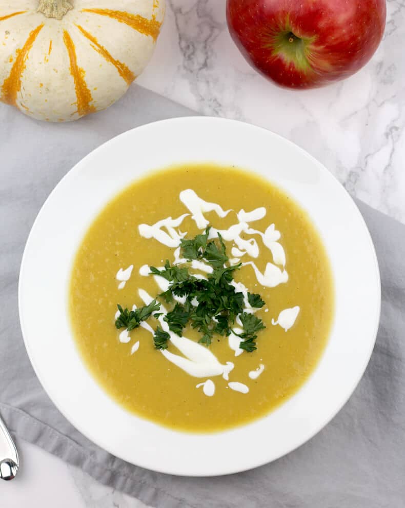 A bowl of butternut squash soup drizzled with sour cream and parsley.
