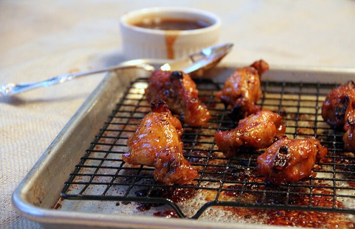 Side view of a few baked chicken wings in a pan.