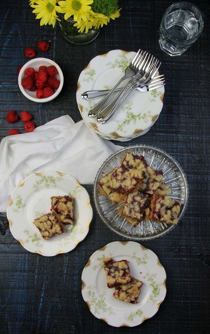 A platter of raspberry bars with more bars on plates next to it.