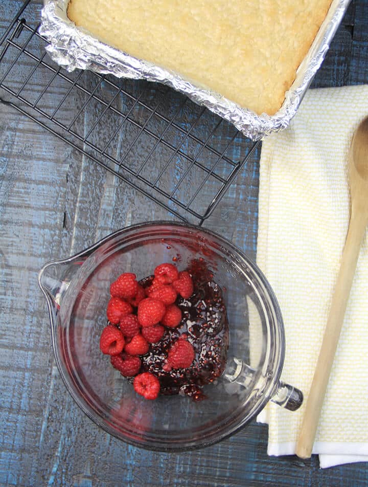 A bowl of raspberry jam and fresh raspberries to make raspberry bars.