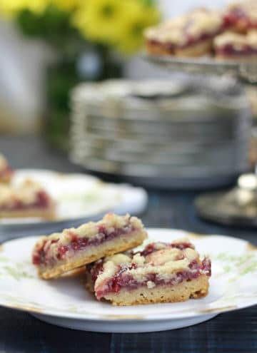 Raspberry bars on a plate with the platter in the background.