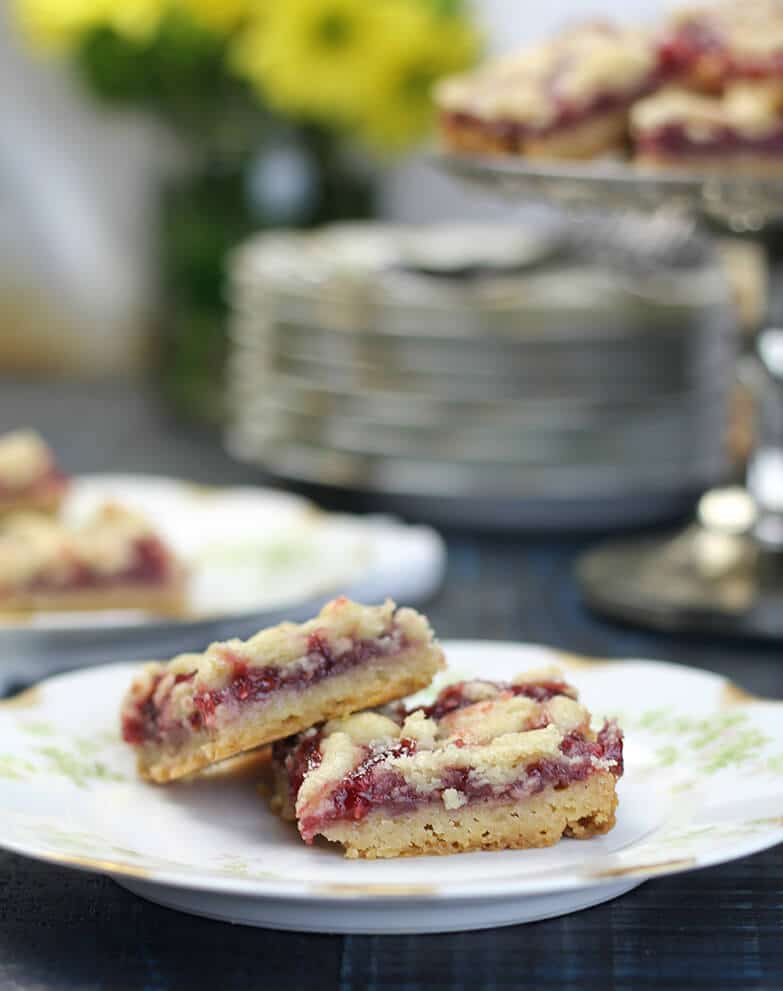 Raspberry bars on a plate with the platter in the background.