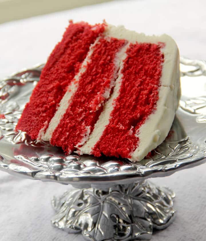 Slice of red velvet cake on a silver platter for dessert for a romantic dinner at home.