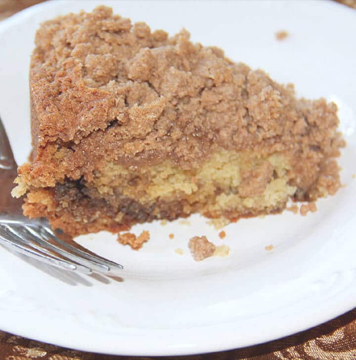 A slice of sour cream coffee cake on a white plate.