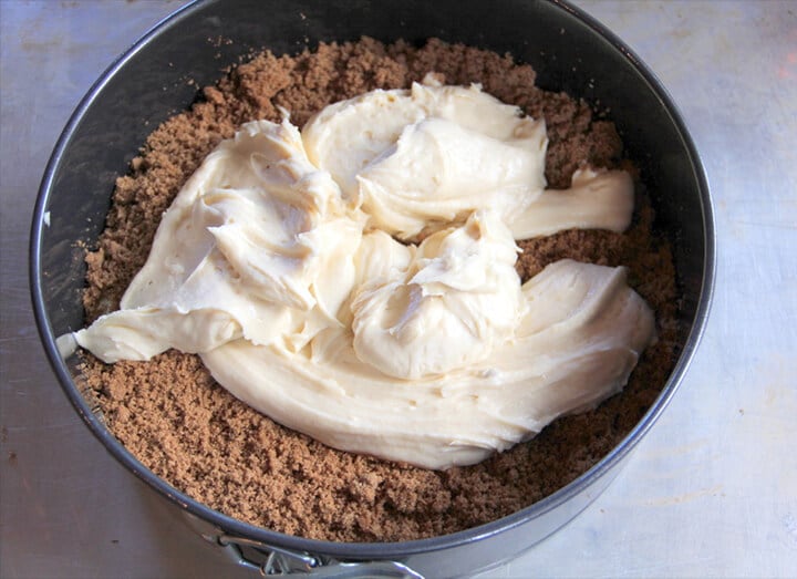A springform pan with dollops of coffee cake batter over filling.