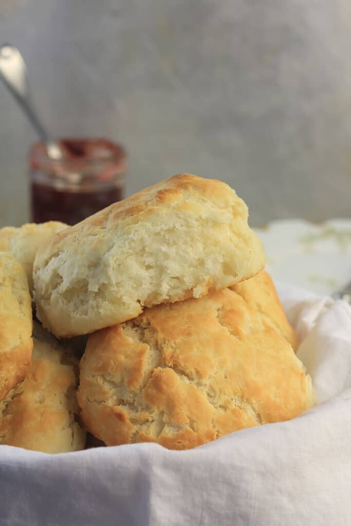 Basket of biscuits with jam and plates.