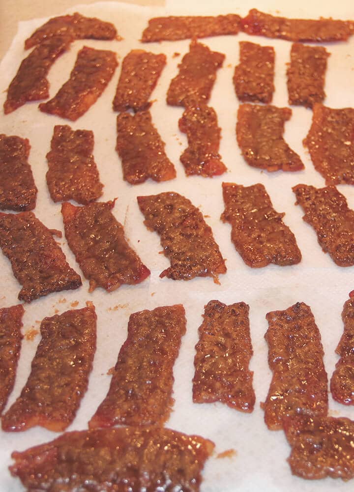 Pieces of caramelized bacon on a platter lined with parchment.
