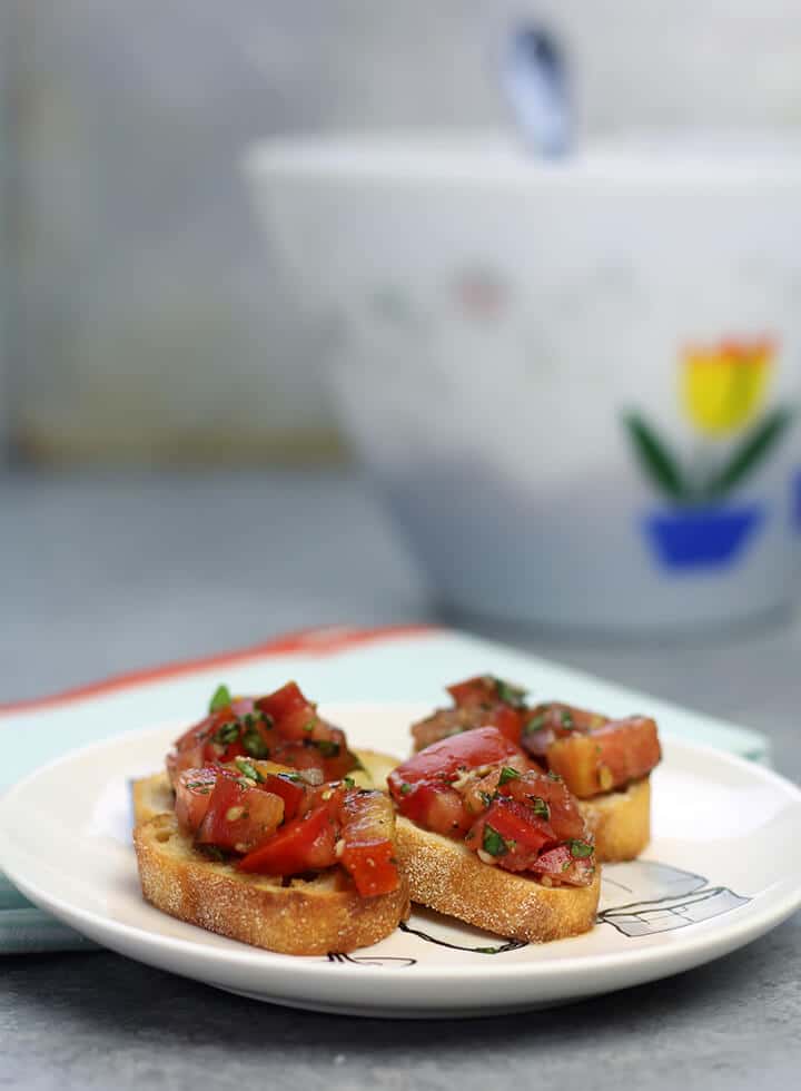 bruschetta appetizer on a plate with a bowl in the background.