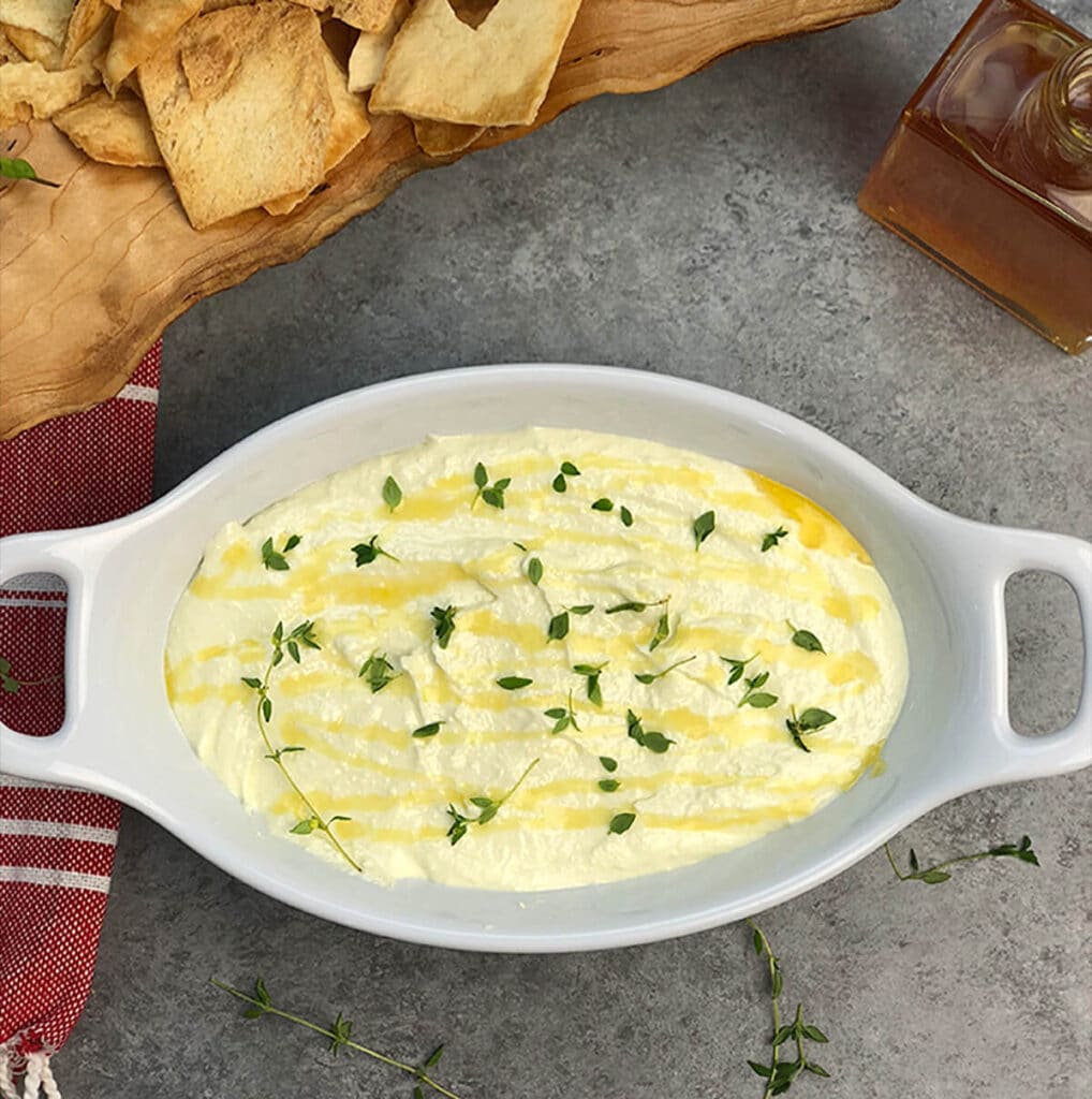 Overhead photo of a bowl of dip with fresh thyme and chips.