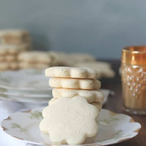 Tea cakes stacked on a plate with a glass of milk.
