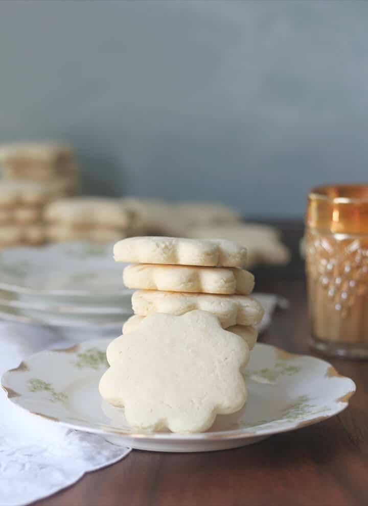 Tea cakes stacked on a plate with a glass of milk.