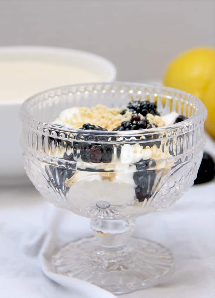 A bowl of lemon cream and berries with lemons in background.