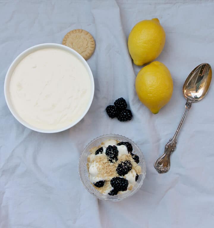 Overhead photo of a bowl of lemon cream cheese with lemons and berries.