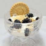 A bowl of berries and lemon pastry cream with a shortbread cookie.