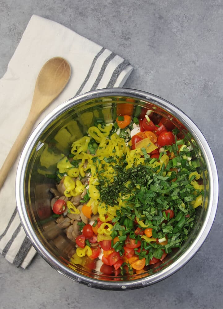 Stainless steel bowl with ingredients for pizza pasta salad.