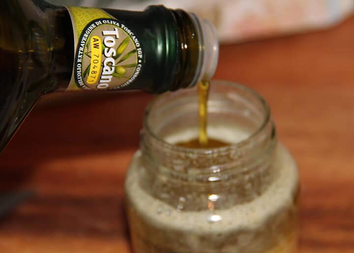 Pouring olive oil into a jar to make a vinaigrette.