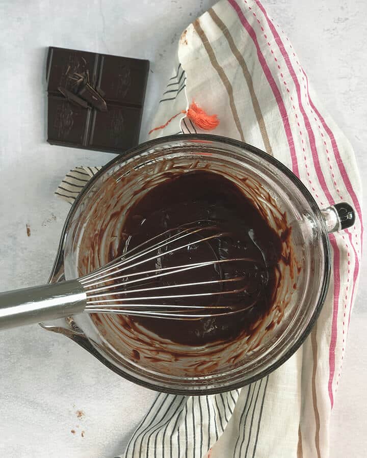 Bowl of melted chocolate and a whisk to make chocolate molten lava cake.