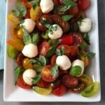 Cherry Tomato Salad with basil on a white platter.