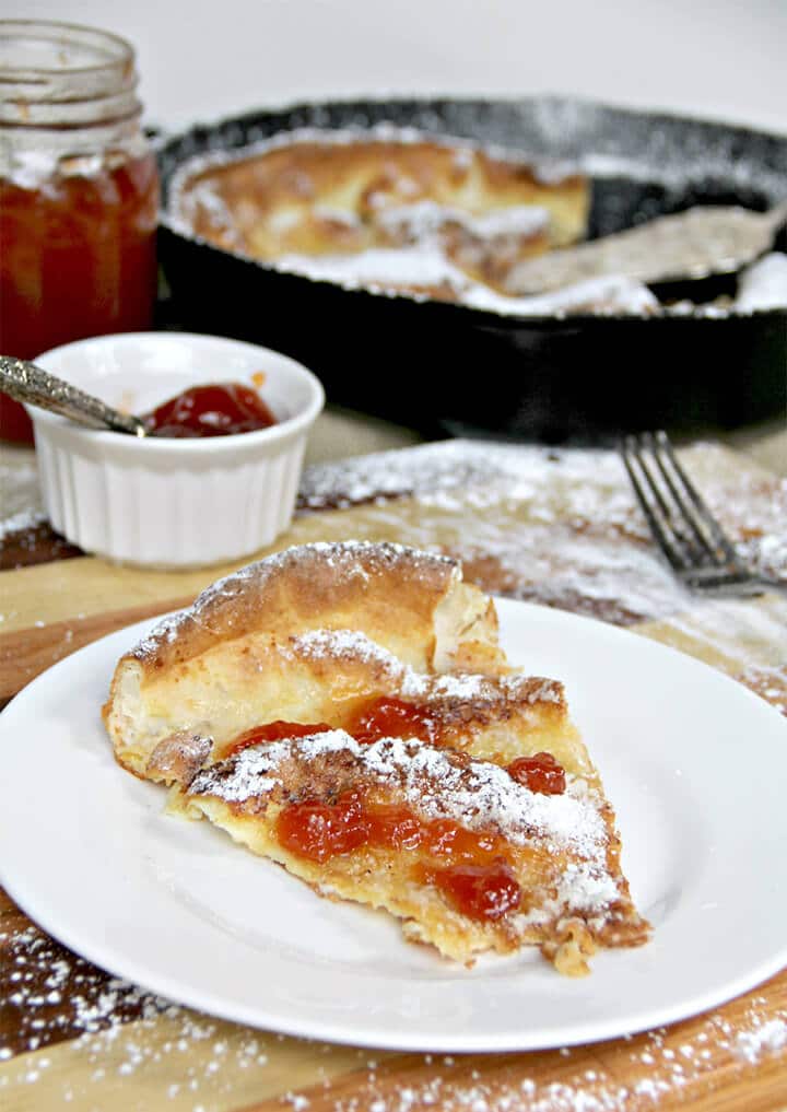 Slice of a dutch baby german pancake on a plate with jelly on top.