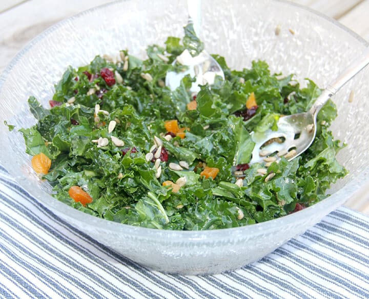 Side view of a bowl of easy kale salad on a table with a blue and white towel.