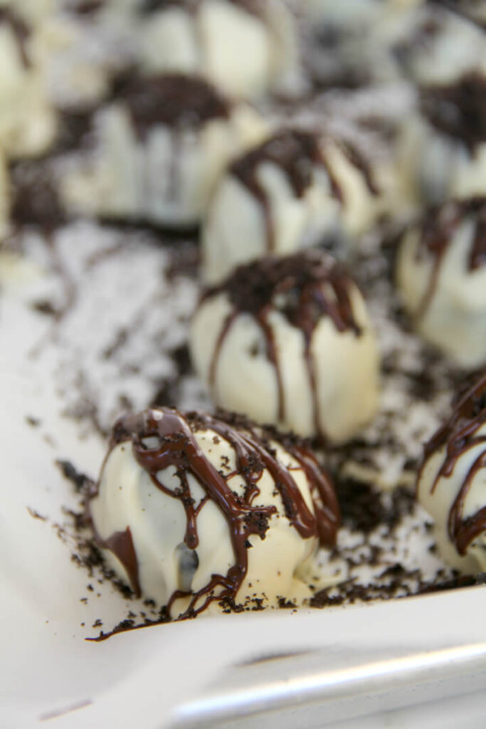 White chocolate covered Oreo balls drizzled with chocolate on a tray.