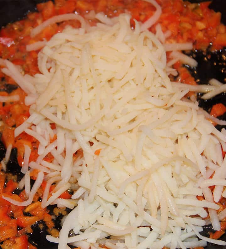 Peppers and hashbrowns cooking in a skillet.