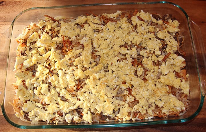 Scrambled eggs over hash browns in a baking dish.