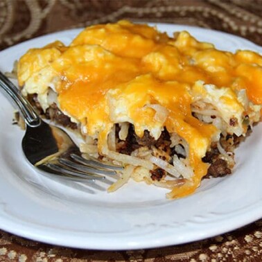 A serving of sausage breakfast pizza on a white plate.