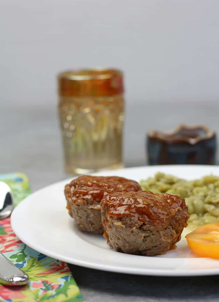 Meatloaf muffins on a plate with butterbeans and tomato.