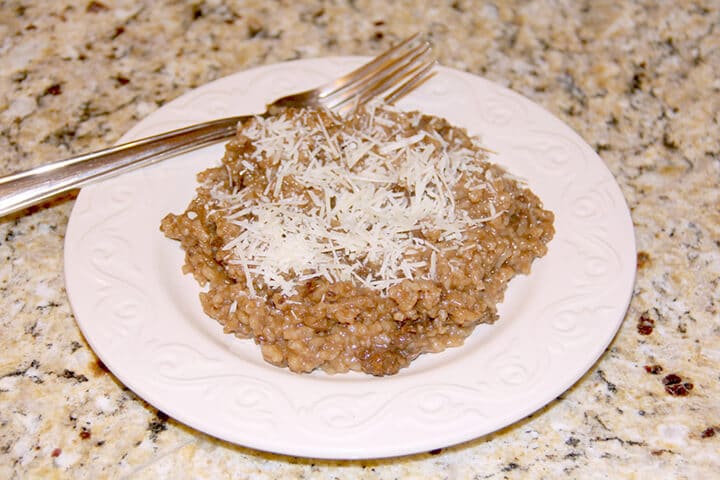 Sausage mushroom risotto on a plate with a fork.