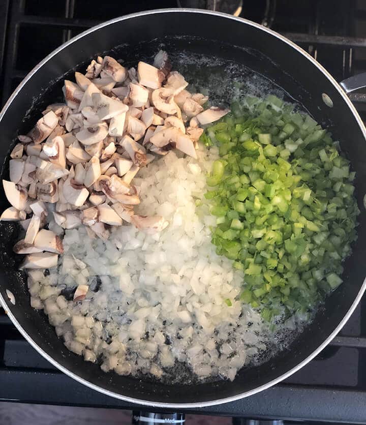 Onions, celery, and mushrooms in a skillet.