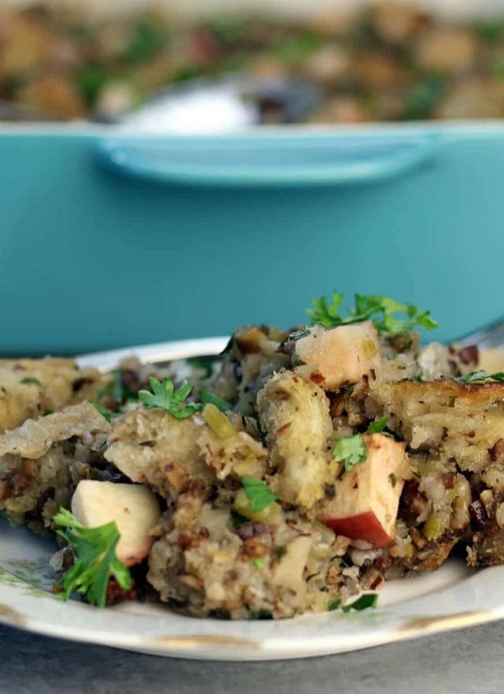 A serving of apple sausage stuffing on a plate with the dish in the background.