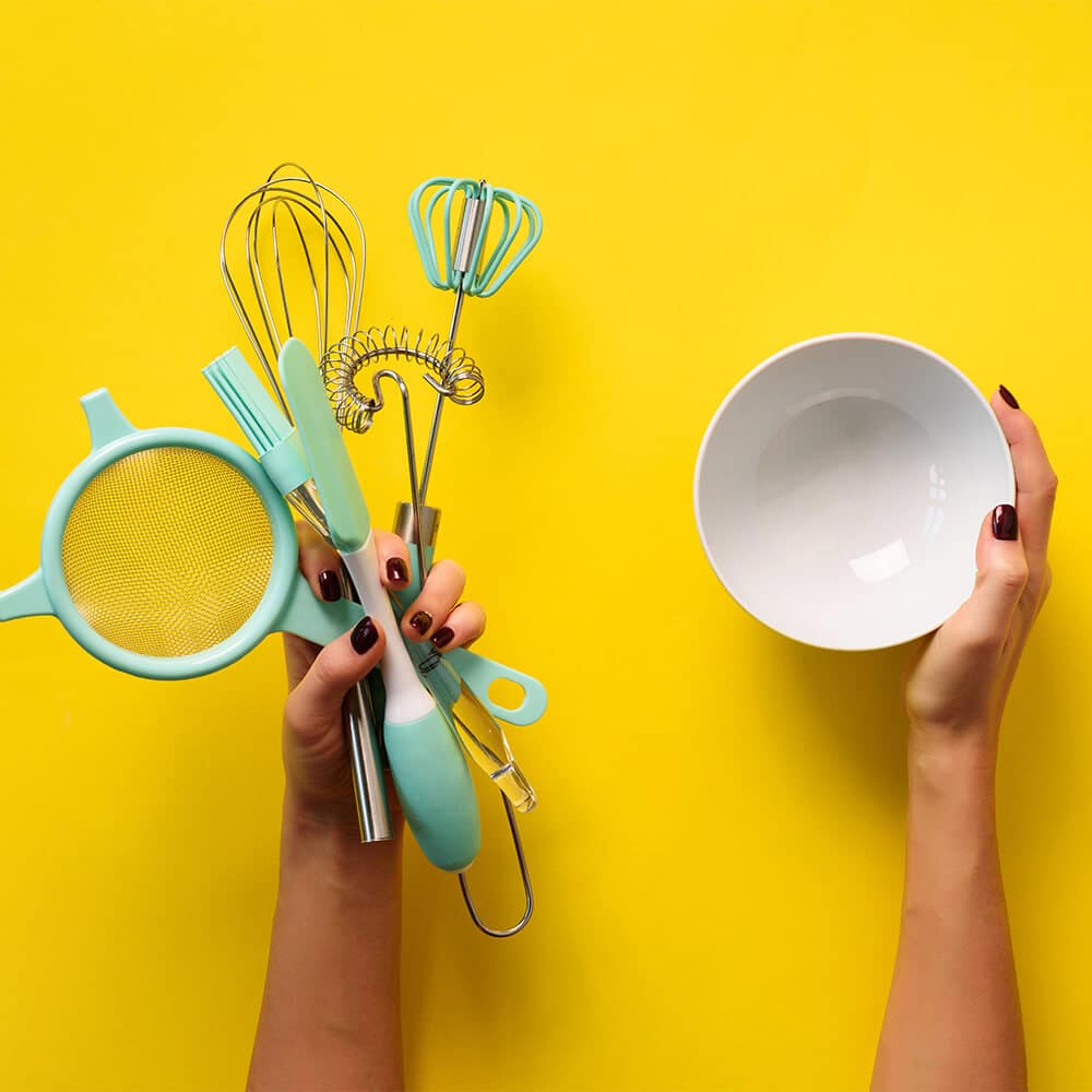 kitchen tools and a white bowl on a yellow background.