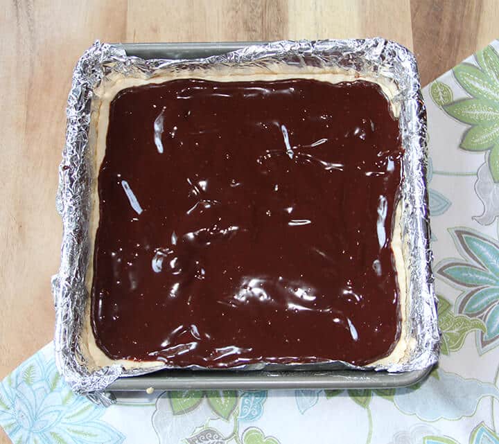 Chocolate ganache spread over shortbread in a pan.