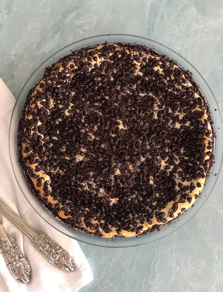 Baked whole chocolate chip cheesecake with a knife on the side.