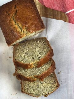 A loaf of banana bread sliced on a sheet of wax paper.