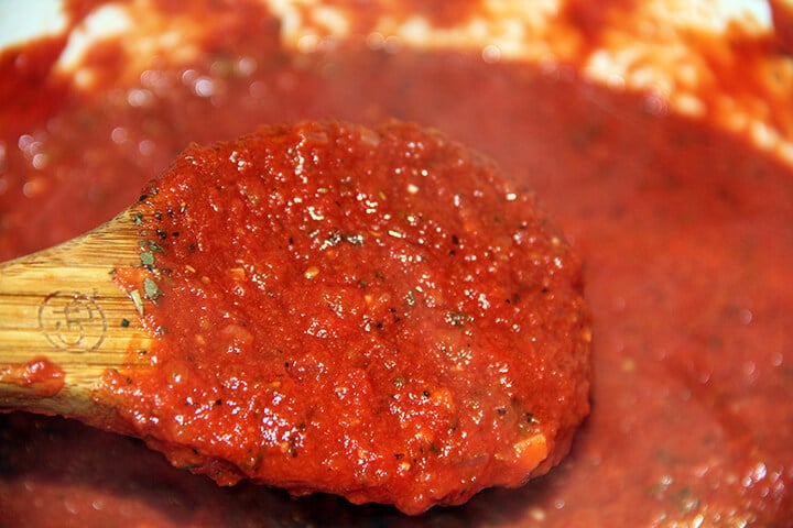 A wooden spoon of easy marinara sauce in a large pot.