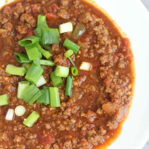 A bowl of chili without beans on the grey counter.