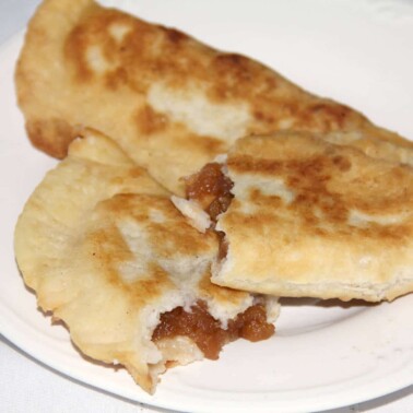 Two fried apple pies on a white plate.