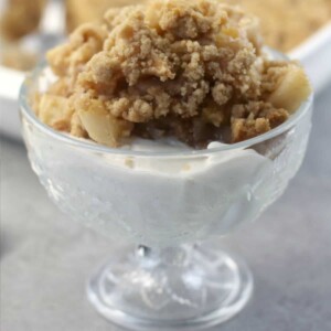 A glass dish of easy apple crisp without oats on top of vanilla ice cream.